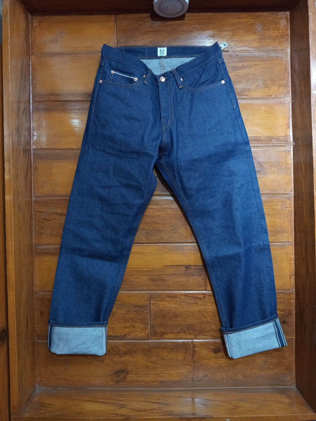 Mith raw indigo selvedge denim jeans flat lay with cuffed hems showing selvedge edge