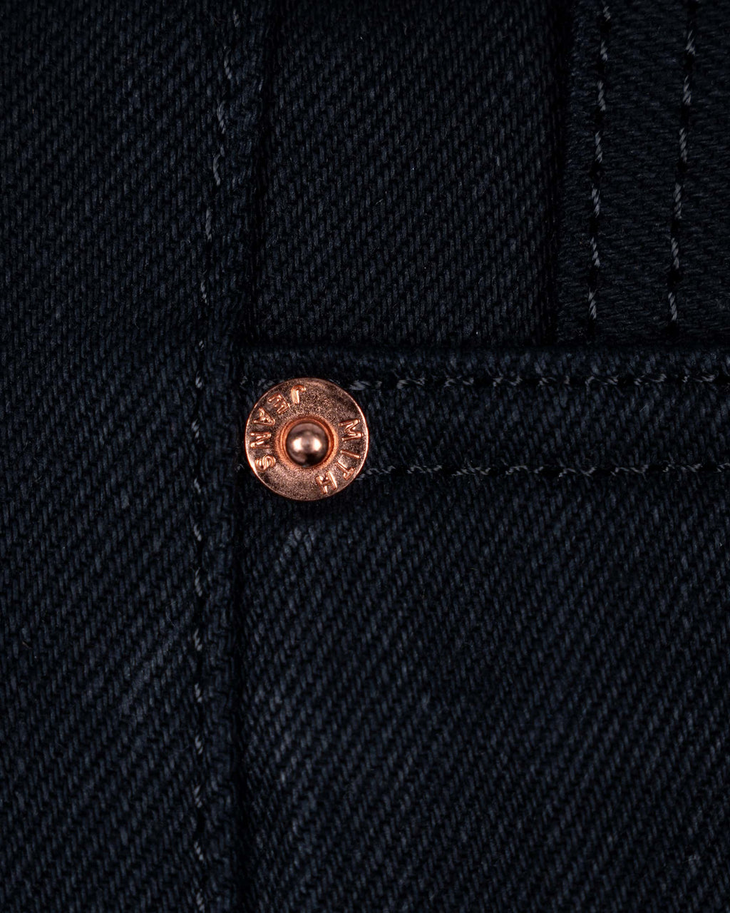 Close-up of 17 oz black selvedge denim jeans showing the  front rivets