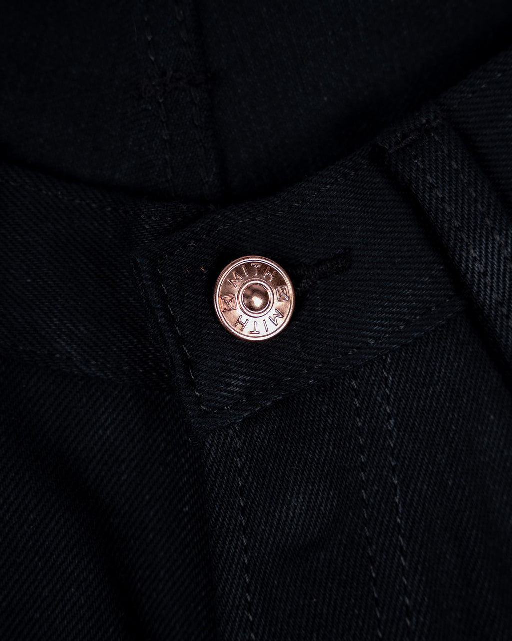 Close-up of 17 oz black selvedge denim jeans showing the waist button