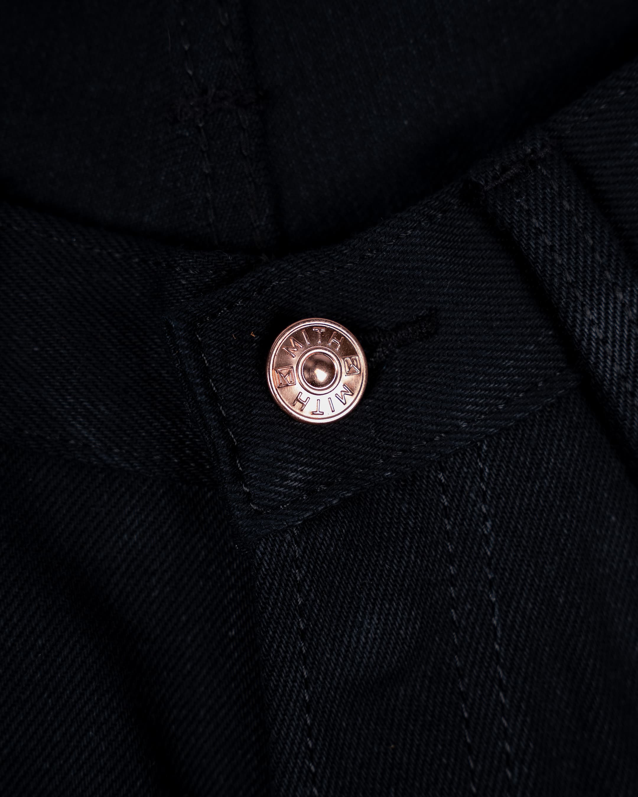 Close-up of 17 oz black selvedge denim jeans showing the waist button