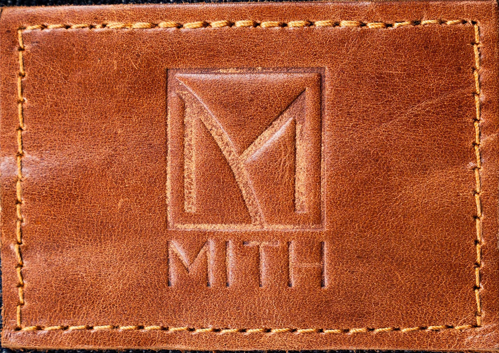 Close-up of a brown leather patch with a stitched border and an embossed MITH logo.