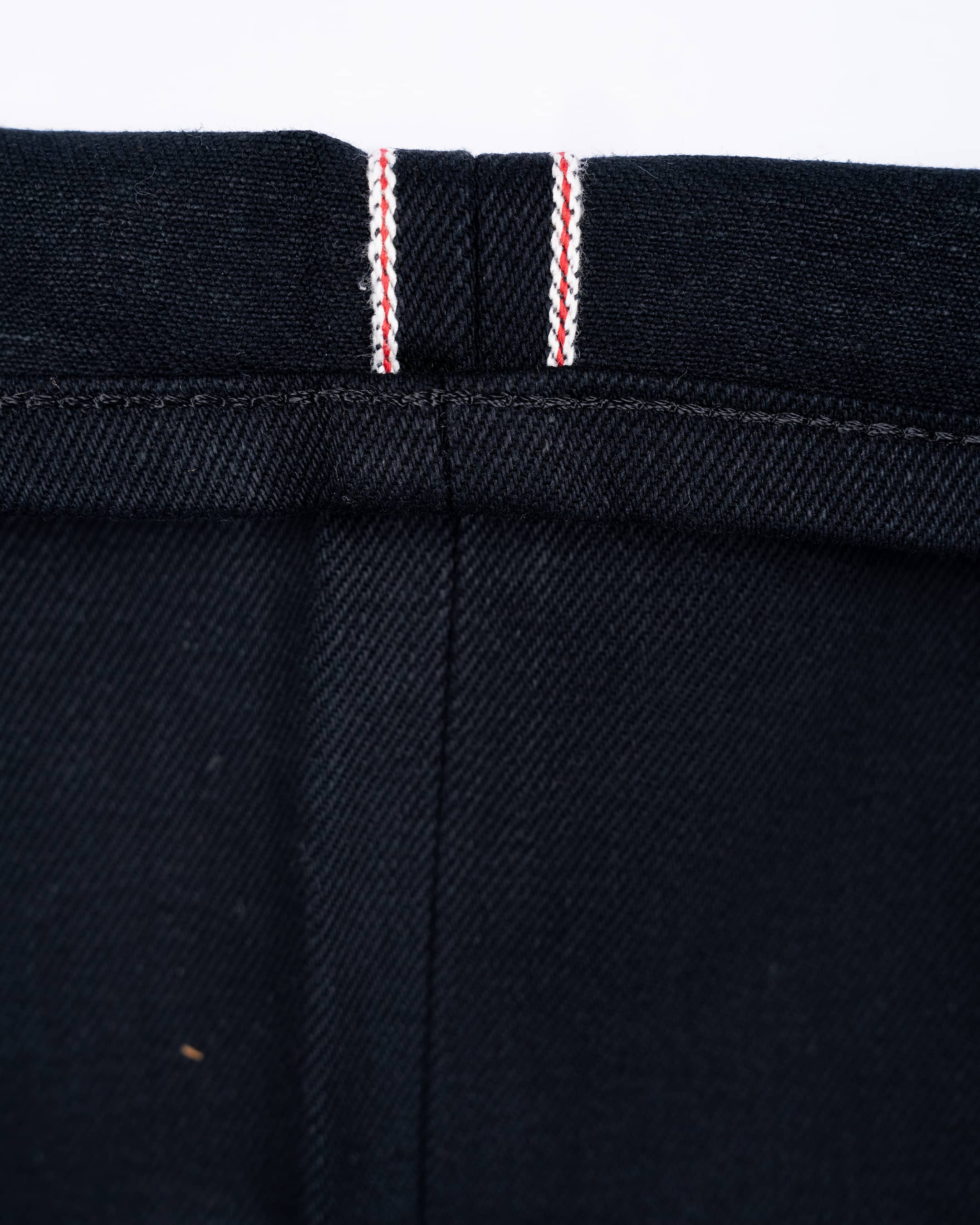 Close-up of 17oz black selvedge denim jeans showing the hem and selvedge id.