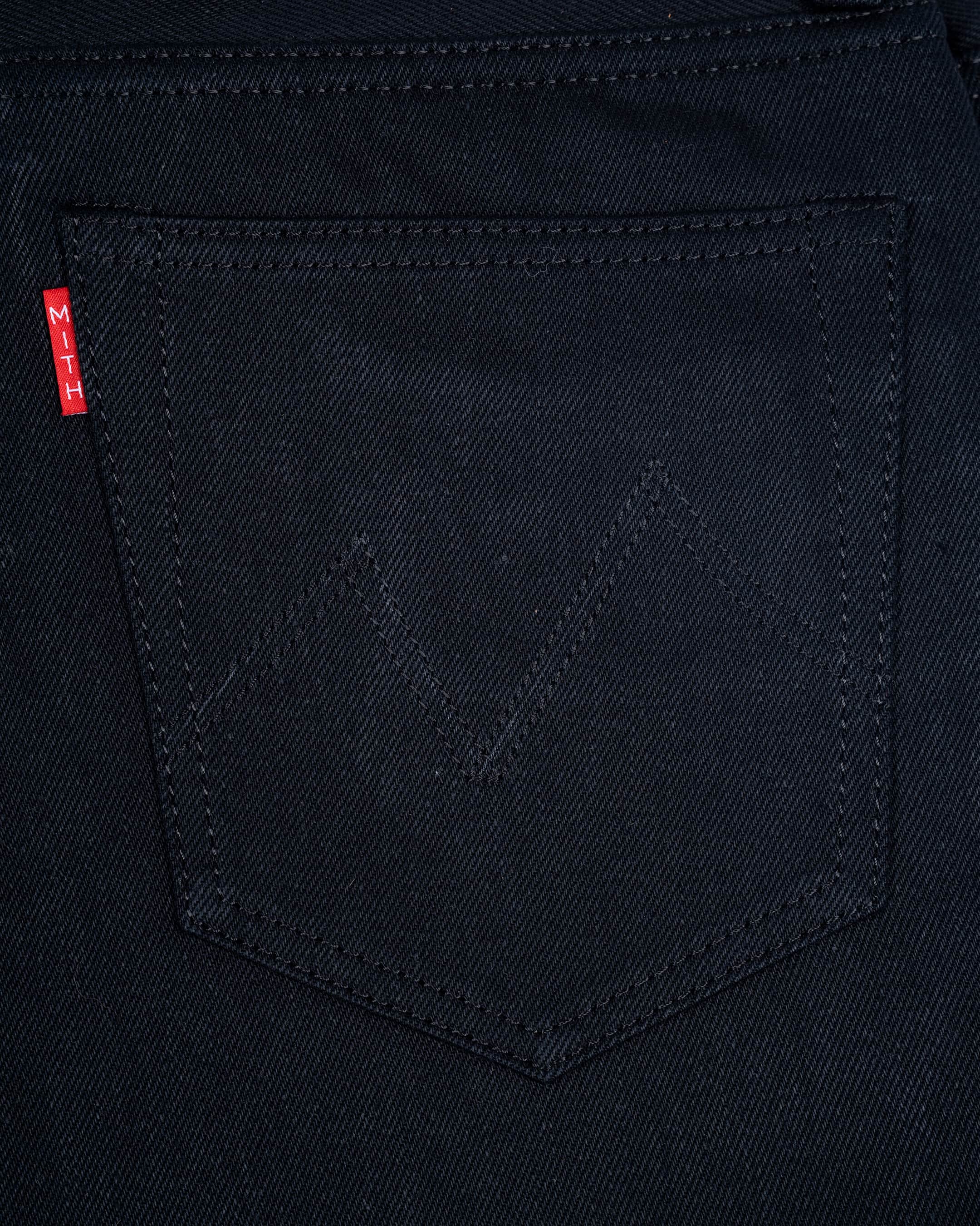 Close-up of a17oz black denim back pocket with a subtle tonal zigzag stitch detail(Mt. Everest) and a small red Mith's brand tab on the left edge.
